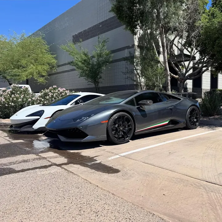 Grey Lamborghini Huracán Performante with an Italian-flag stripe, parked beside a white McLaren