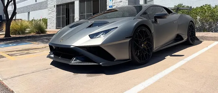 Matte grey Lamborghini Huracán STO with black wheels, parked outside the shop