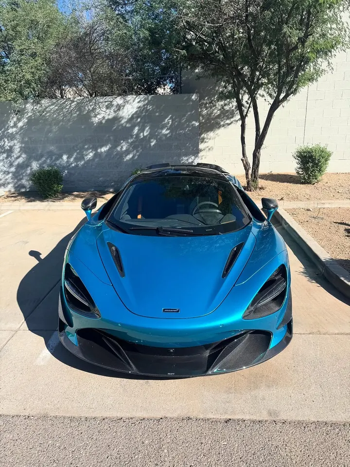 Blue McLaren 720S seen head-on from above, parked outside the shop
