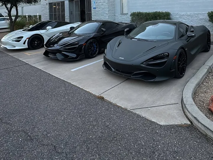 White, black and matte grey McLaren supercars parked side by side outside the shop