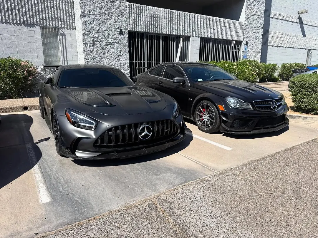 Matte grey Mercedes-AMG GT Black Series and black C63 AMG Black Series parked outside the shop