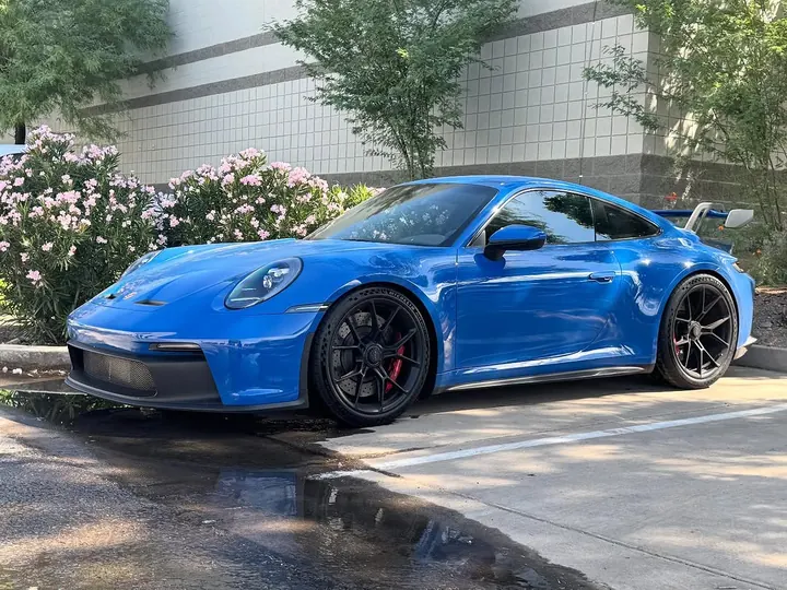 Blue Porsche 911 GT3 (992) with black wheels, parked outside the shop