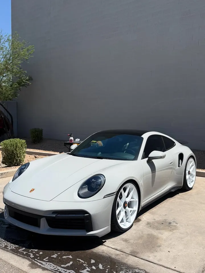 Chalk Porsche 911 Turbo S (992) with white wheels, parked outside the shop