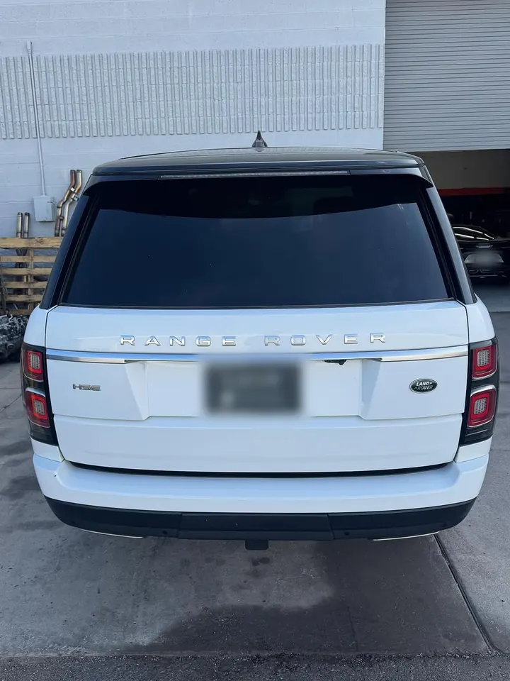 White Range Rover HSE (L405) seen from behind, parked by the shop’s open garage door