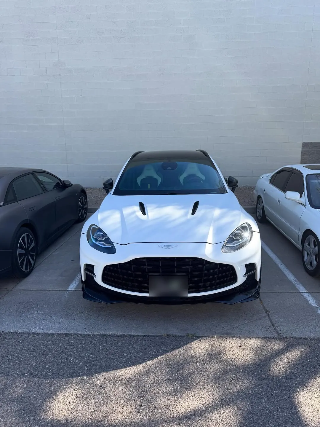 Front view of a white Aston Martin DBX707 with a black roof in a parking lot