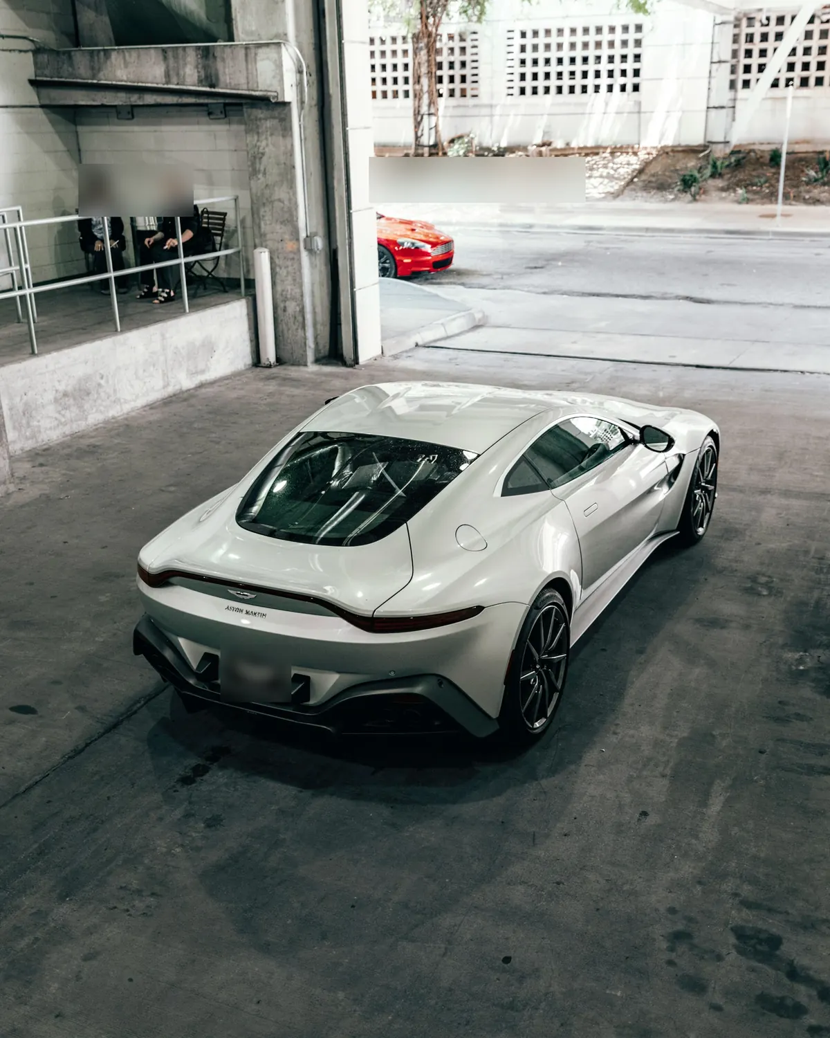 Rear three-quarter view from above of a white Aston Martin Vantage V8 in a parking garage