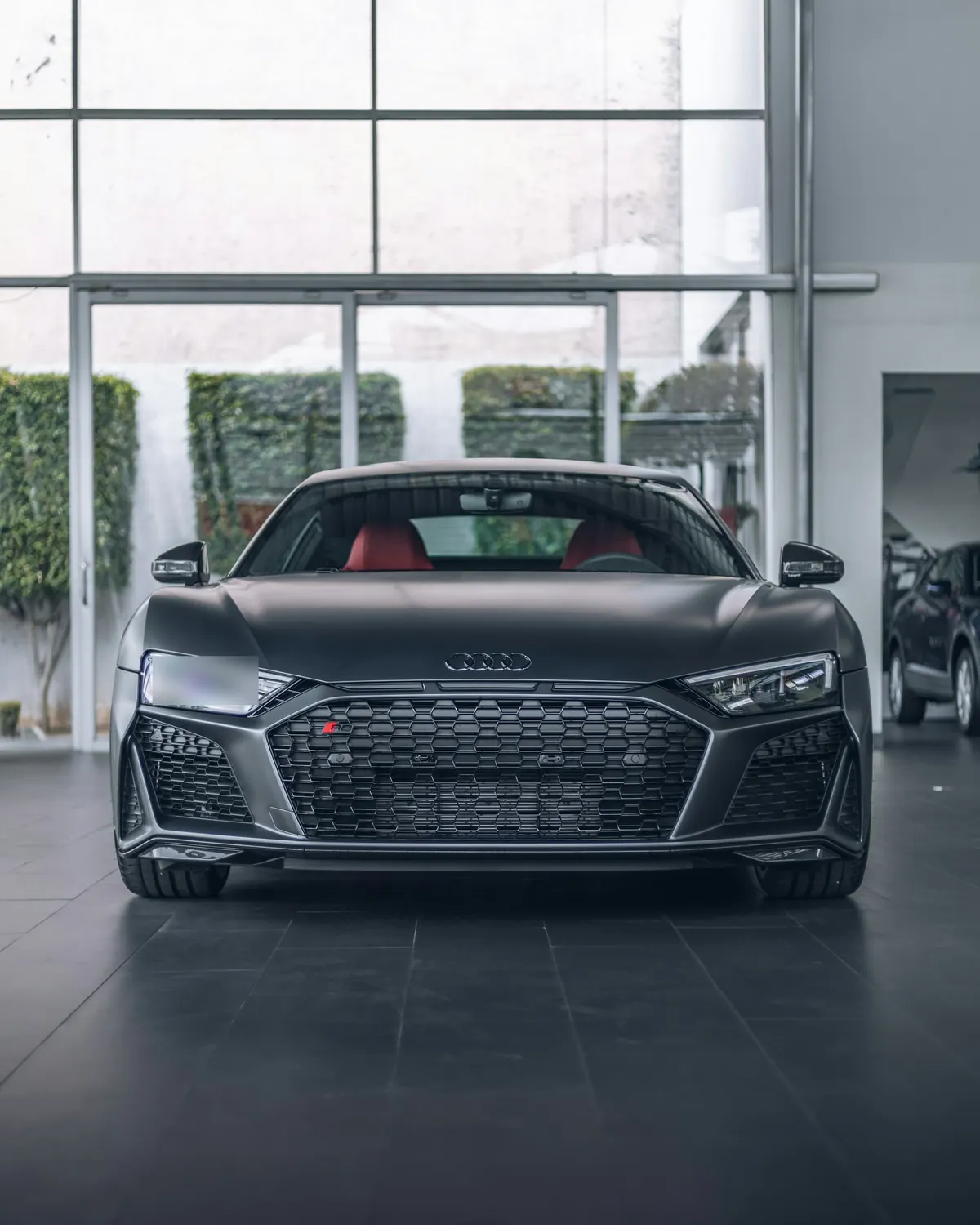 Front view of a matte grey Audi R8 V10 performance in a showroom