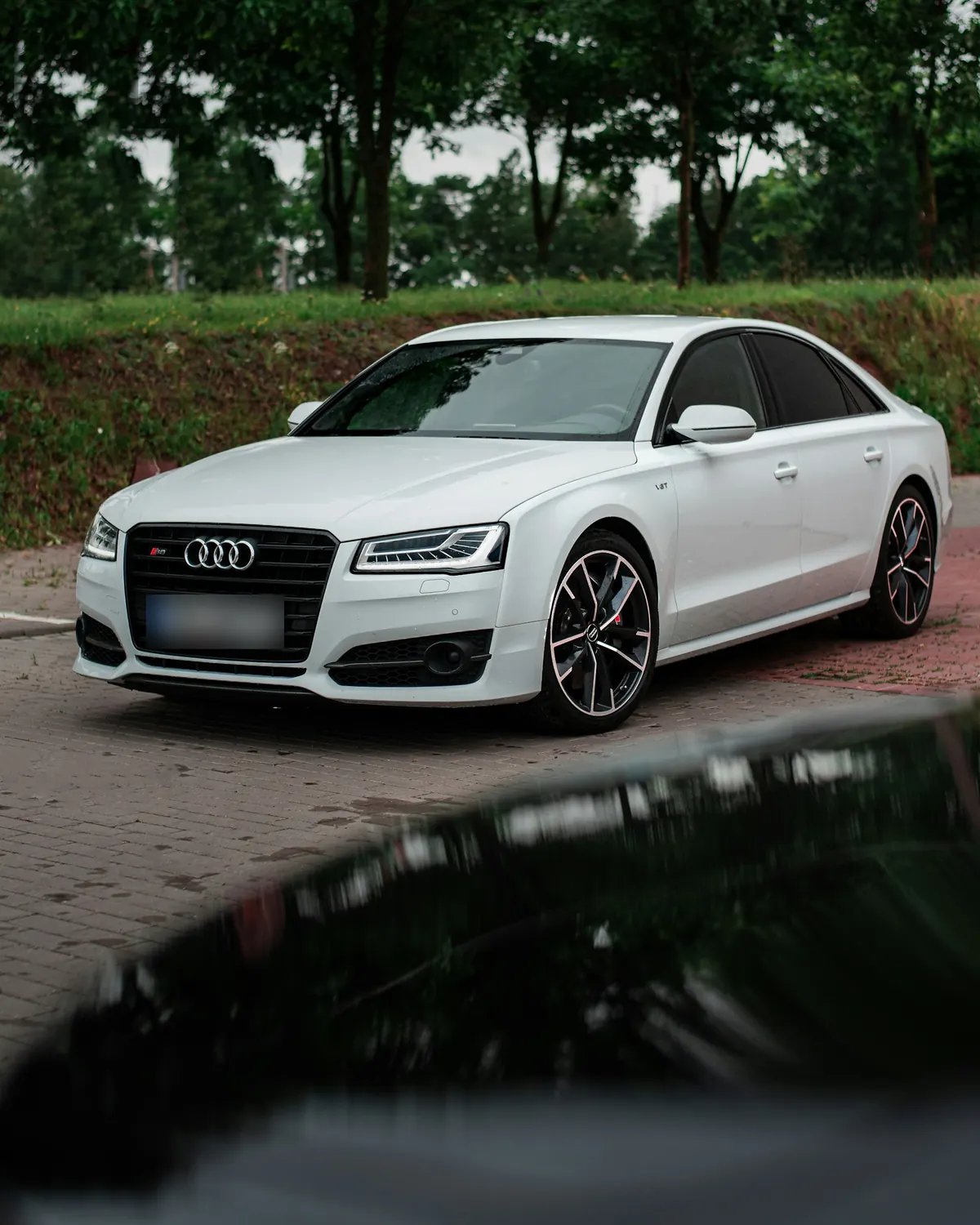 Front three-quarter view of a white Audi S8 (D4) parked on a brick road