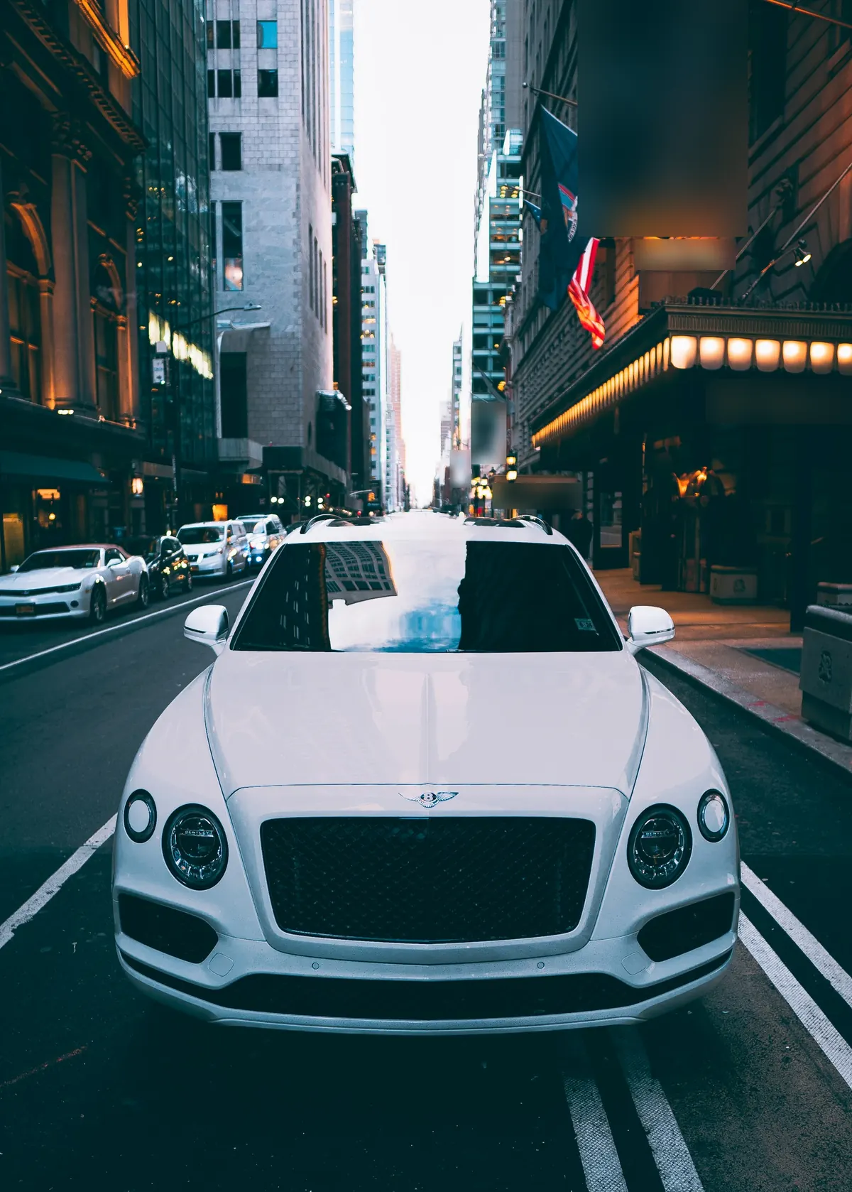 Front view of a white Bentley Bentayga V8 on a city street