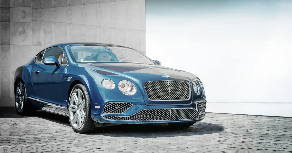 Front three-quarter view of a blue Bentley Continental Supersports coupe parked on cobblestones