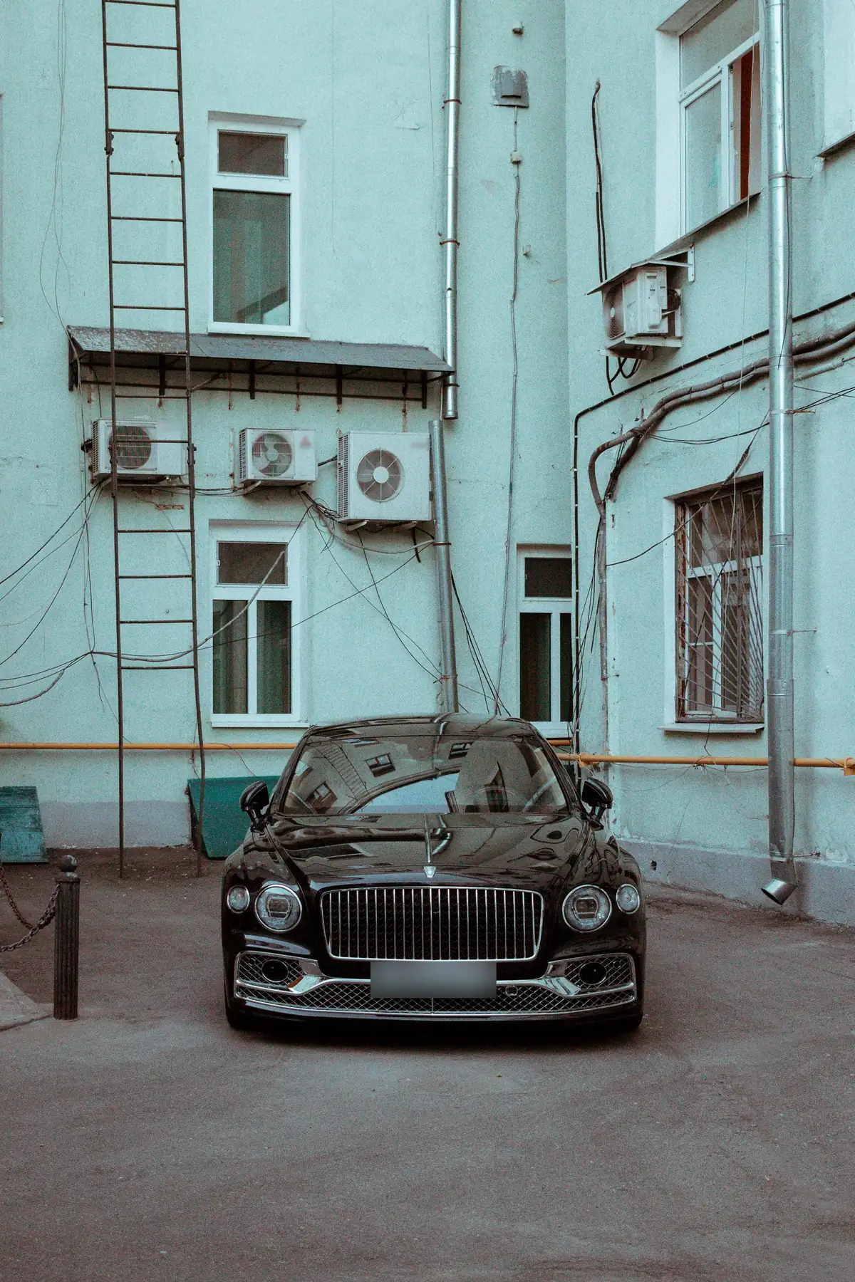 Front view of a black Bentley Flying Spur V8 parked in a courtyard