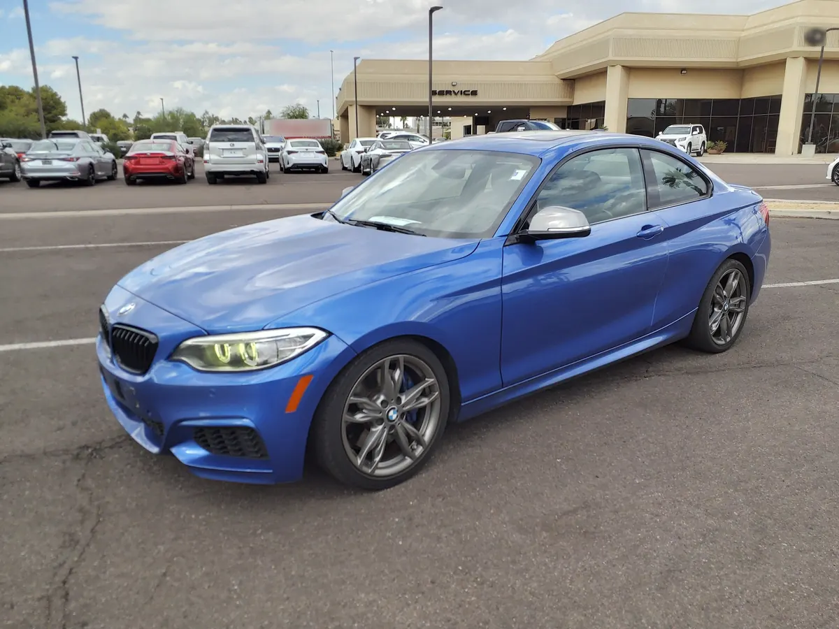 Front three-quarter view of a blue BMW 240i (F22) coupe in a parking lot