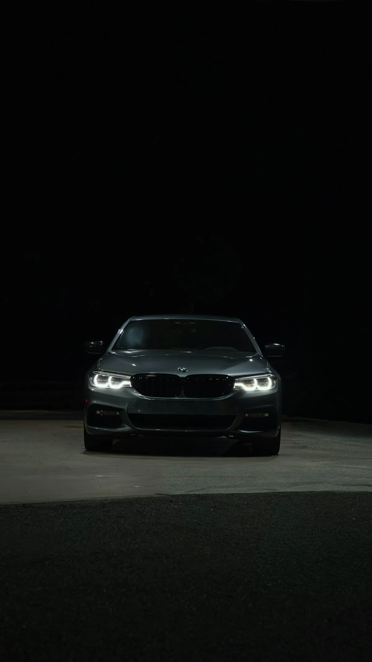 Front view of a grey BMW 540i (G30) sedan at night