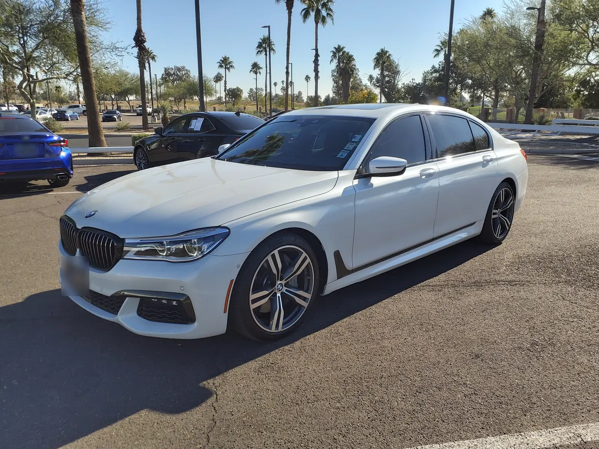 Front three-quarter view of a white BMW 740i (G12) sedan in a parking lot