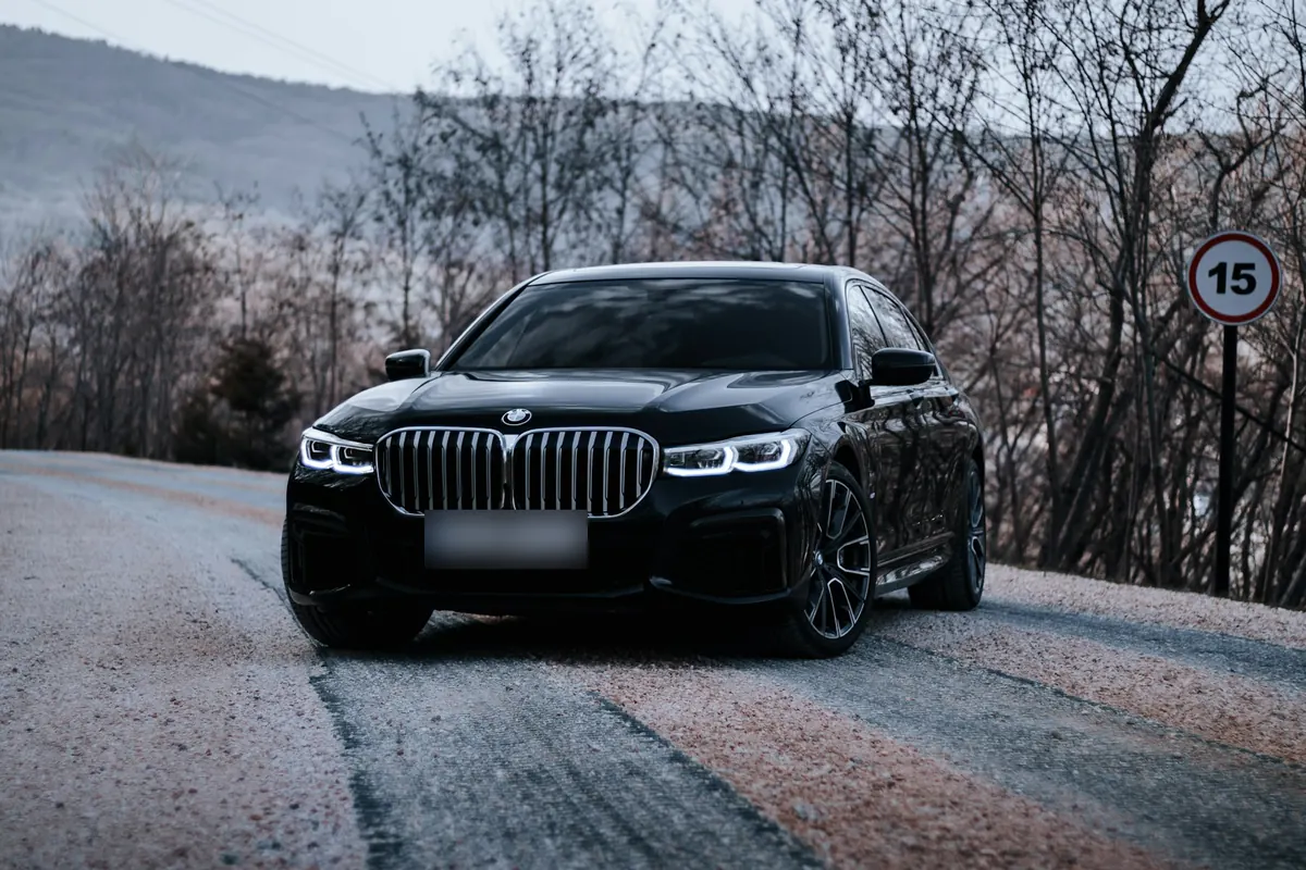 Front three-quarter view of a black BMW 750i xDrive (G11 facelift) on a mountain road