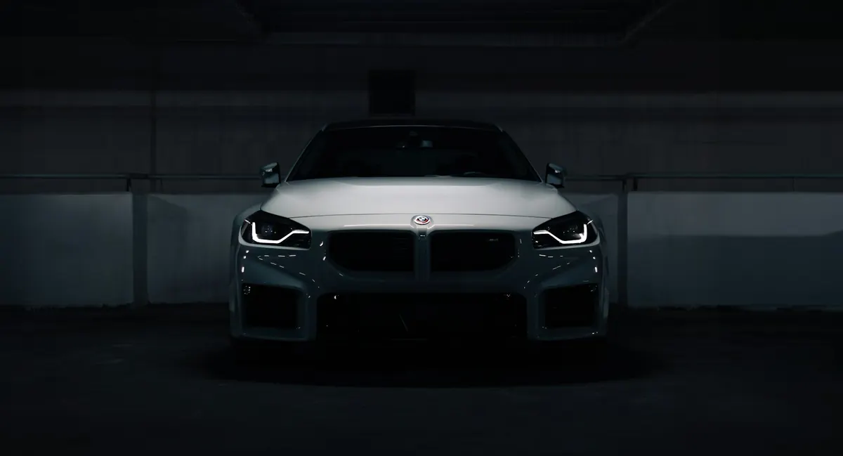 Front view of a white BMW M2 (G87) in a dark parking garage
