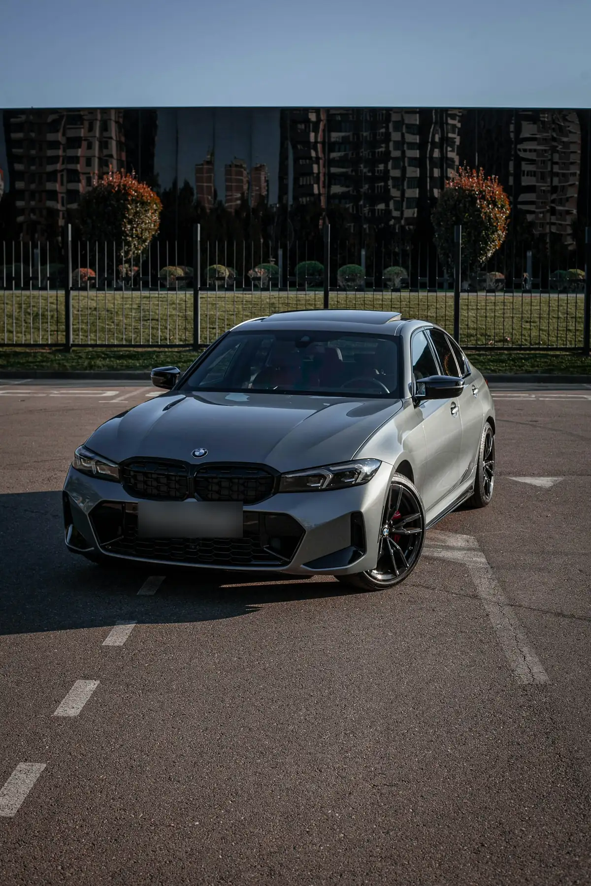 Front three-quarter view of a grey BMW M340i (G20) sedan in a parking lot