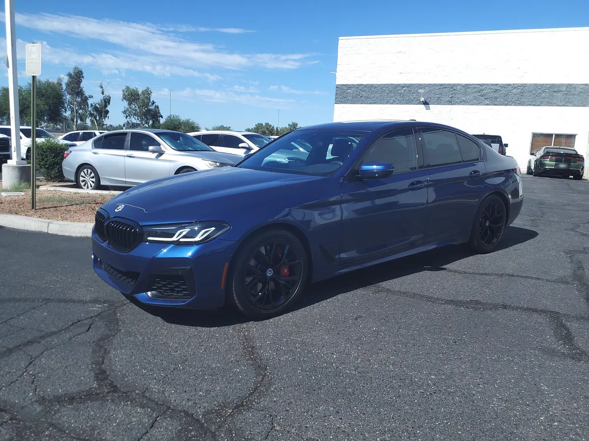 Front three-quarter view of a blue BMW M550i xDrive (G30) sedan in a parking lot