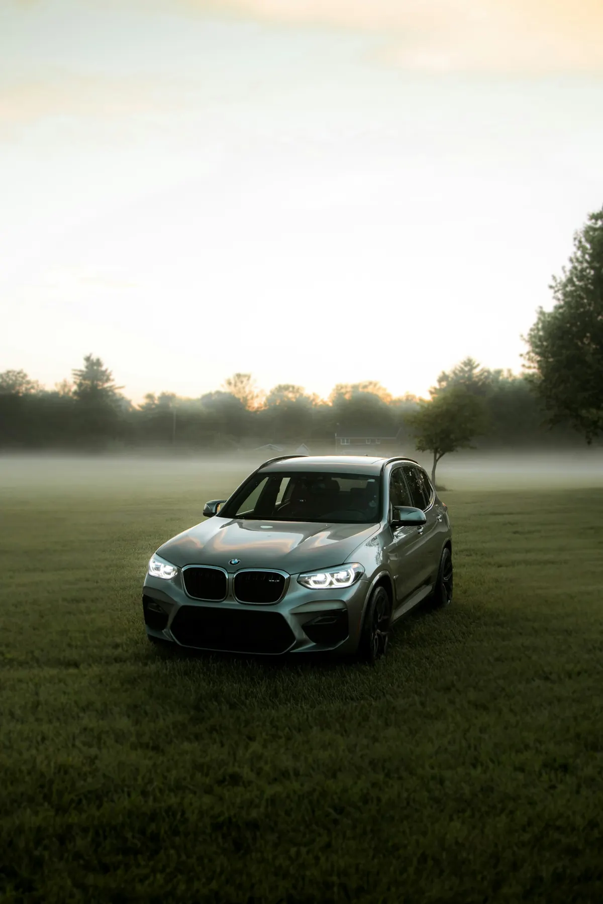 Front three-quarter view of a grey BMW X3 M (F97) in a foggy field