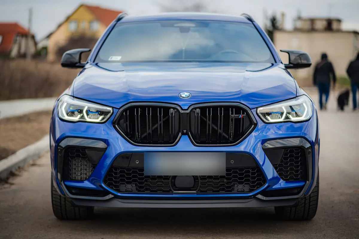 Front view of a blue BMW X6 M (F96) on a village road