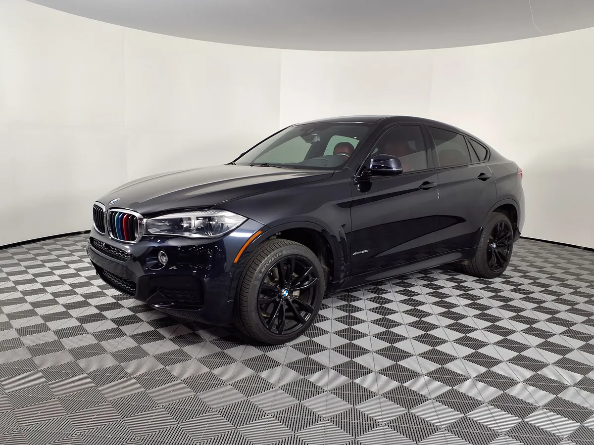 Front three-quarter view of a dark blue BMW X6 xDrive50i in a dealership photo studio