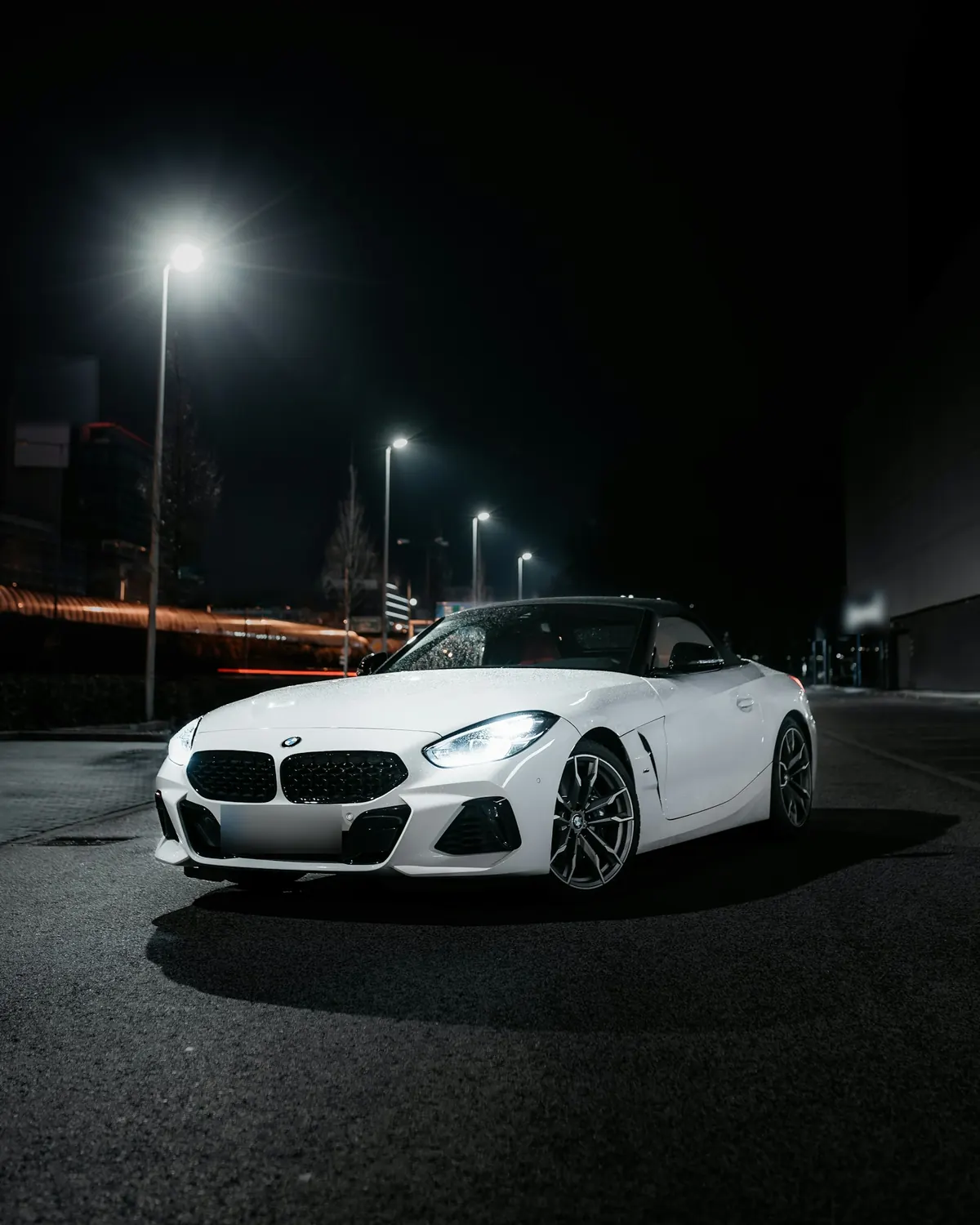 Front three-quarter view of a white BMW Z4 sDrive20i (G29) with its roof up on a street at night