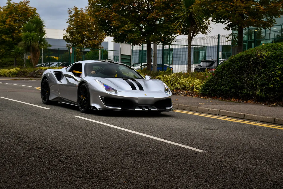 Front three-quarter view of a silver Ferrari 488 Pista with black stripes on a road