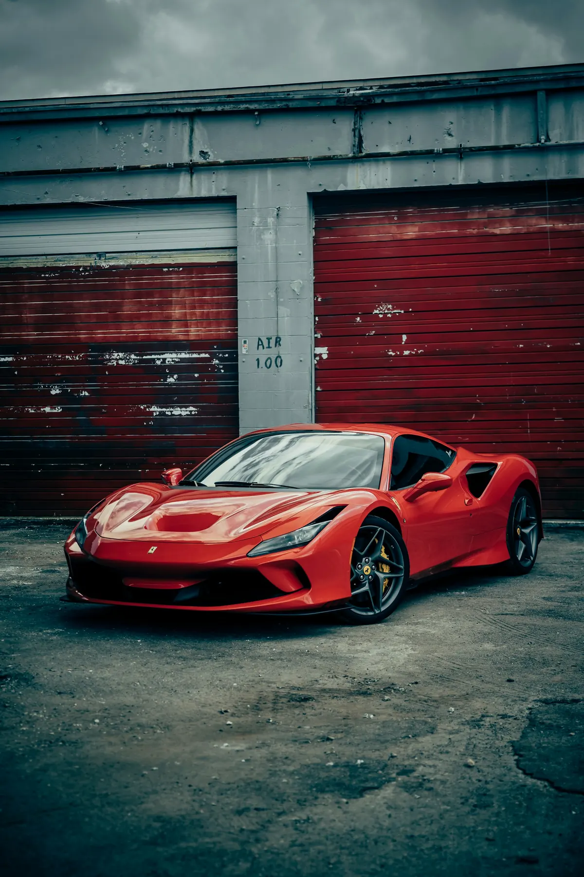 Front three-quarter view of a red Ferrari F8 Tributo in front of red garage doors