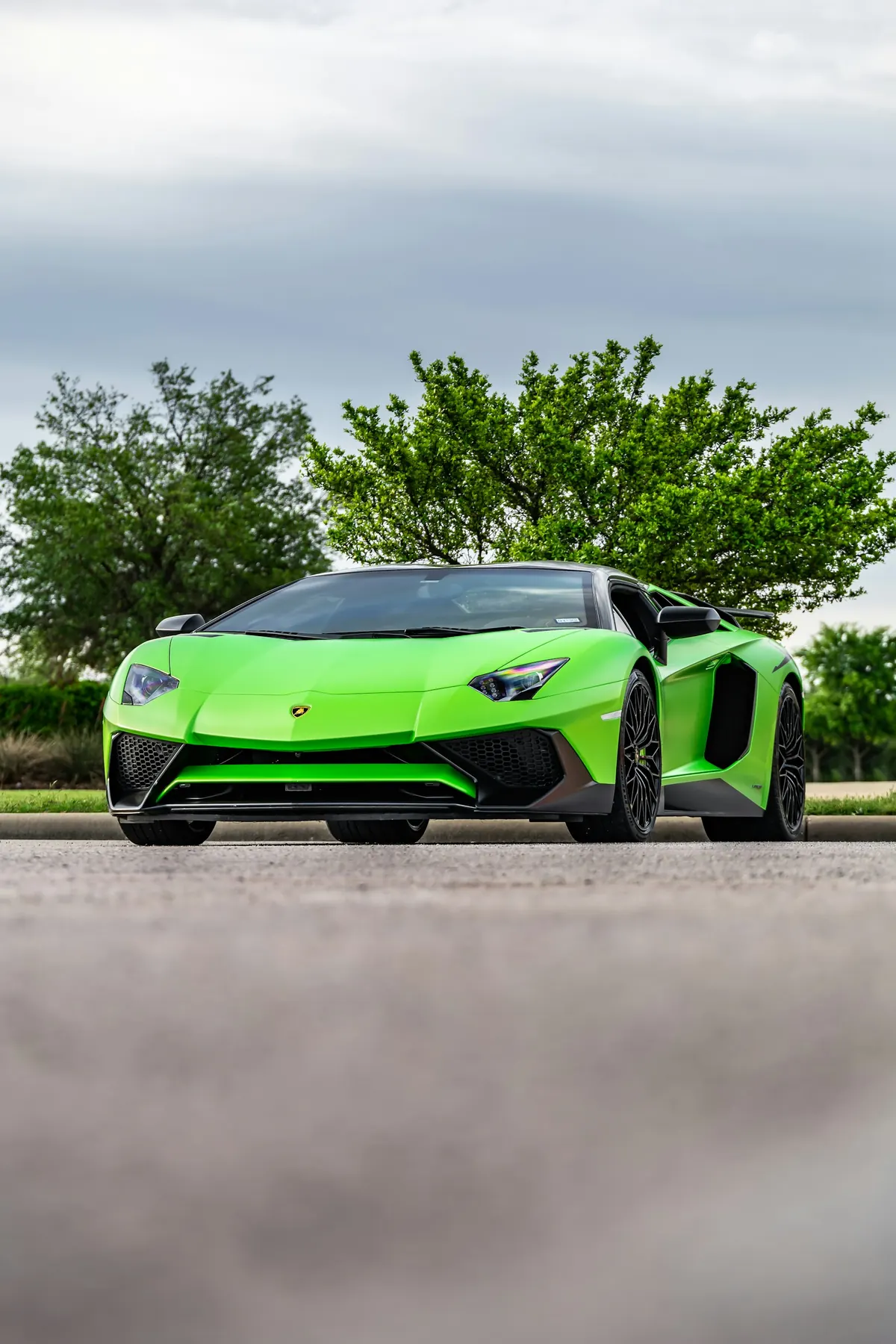 Front three-quarter view of a green Lamborghini Aventador SV with a black roof