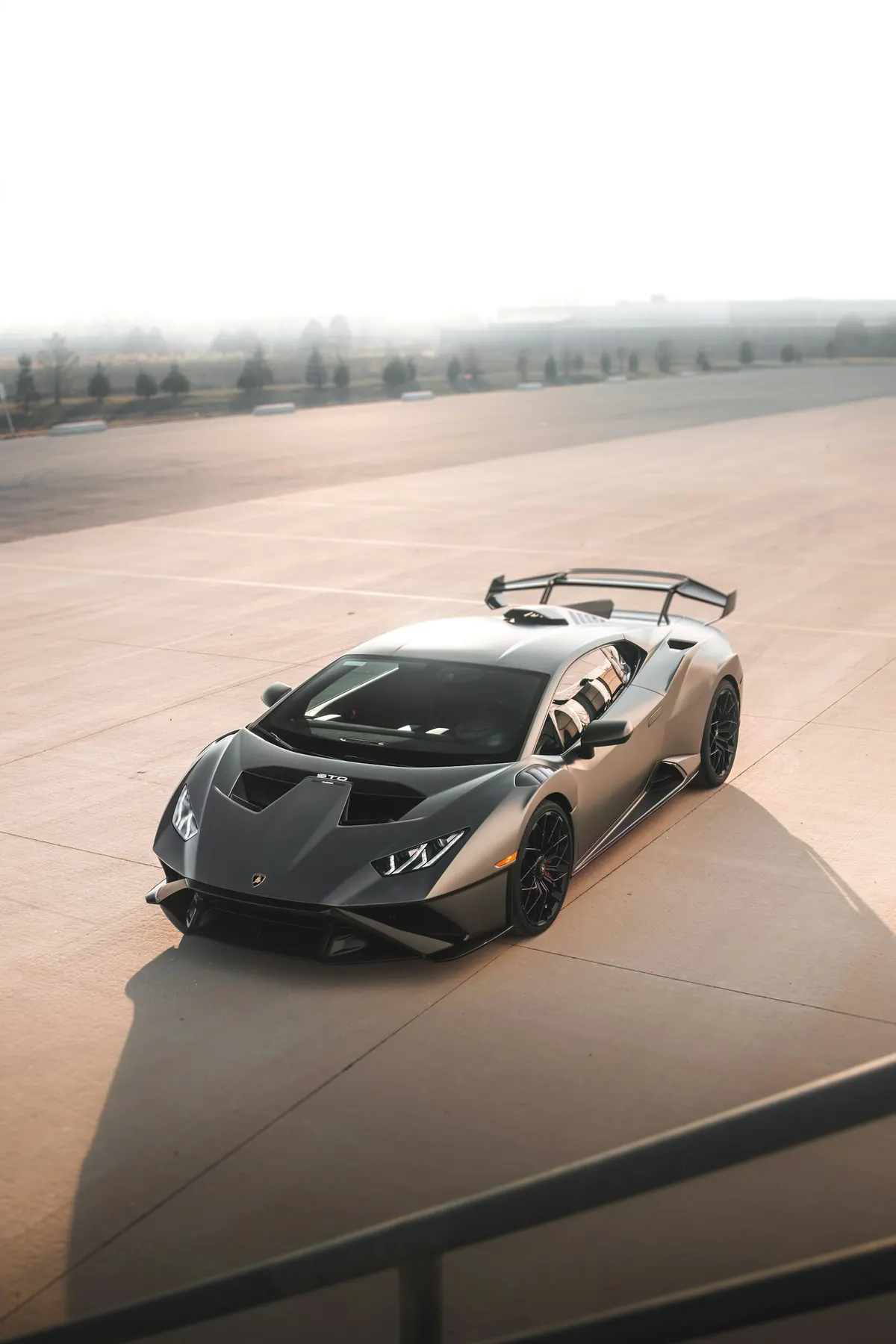 High front three-quarter view of a grey Lamborghini Huracán STO on a concrete track