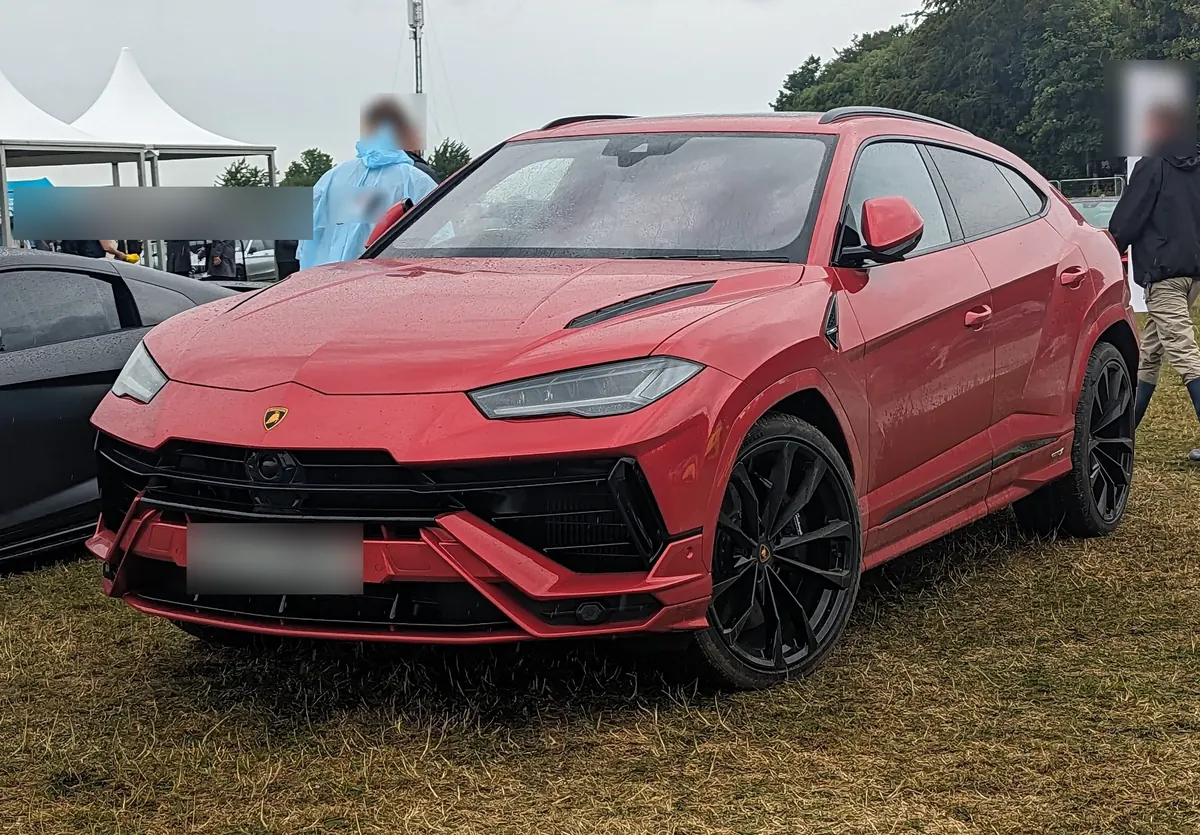 Front three-quarter view of a red Lamborghini Urus S at an outdoor car show