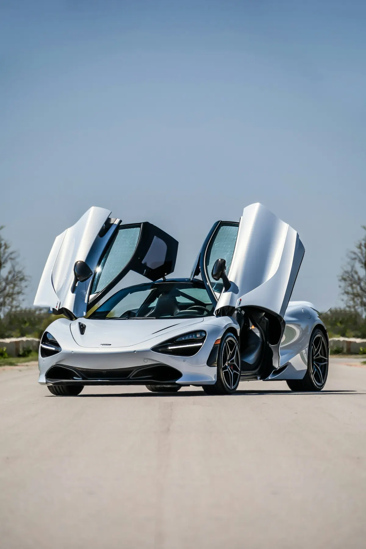 Front three-quarter view of a white McLaren 720S with its dihedral doors open