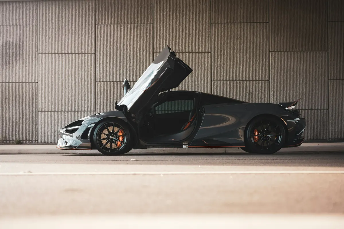 Side view of a dark grey McLaren 765LT with its dihedral door open