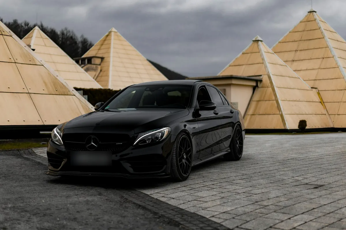 Front three-quarter view of a black Mercedes-AMG C43 (W205) sedan parked in front of pyramid-shaped buildings
