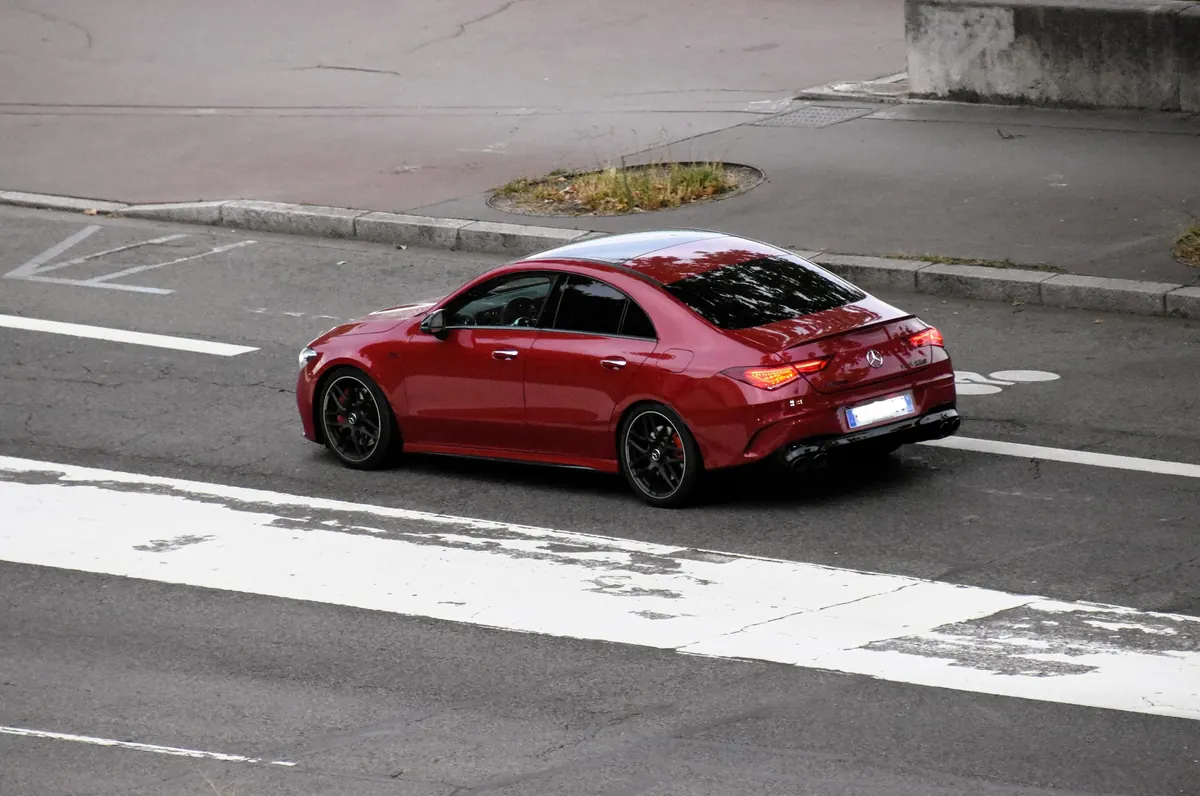 Rear three-quarter view of a red Mercedes-AMG CLA45 (C118) on a city street
