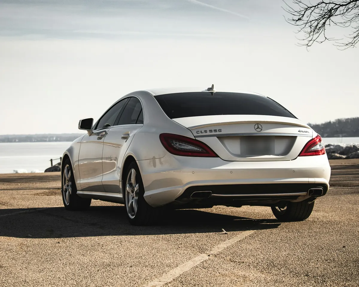 Rear three-quarter view of a white Mercedes-Benz CLS550 (C218) parked by a lake