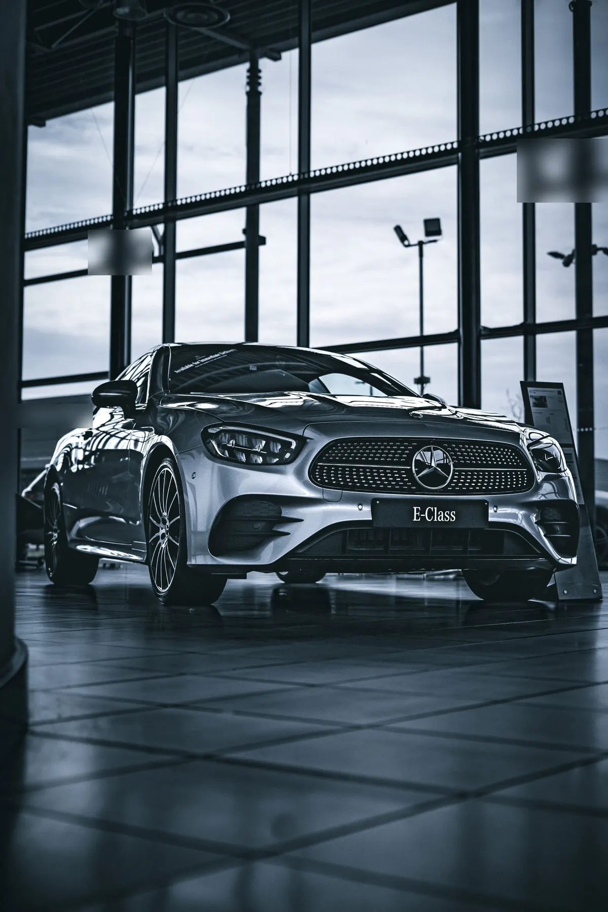 Front three-quarter view of a silver Mercedes-Benz E450 coupe in a showroom
