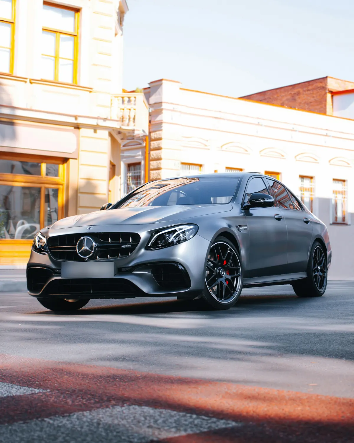 Front three-quarter view of a matte grey Mercedes-AMG E63 S (W213) sedan on a city street
