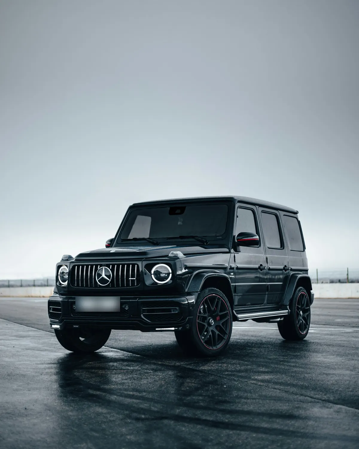 Front three-quarter view of a black Mercedes-AMG G63 (W463A) on a wet track