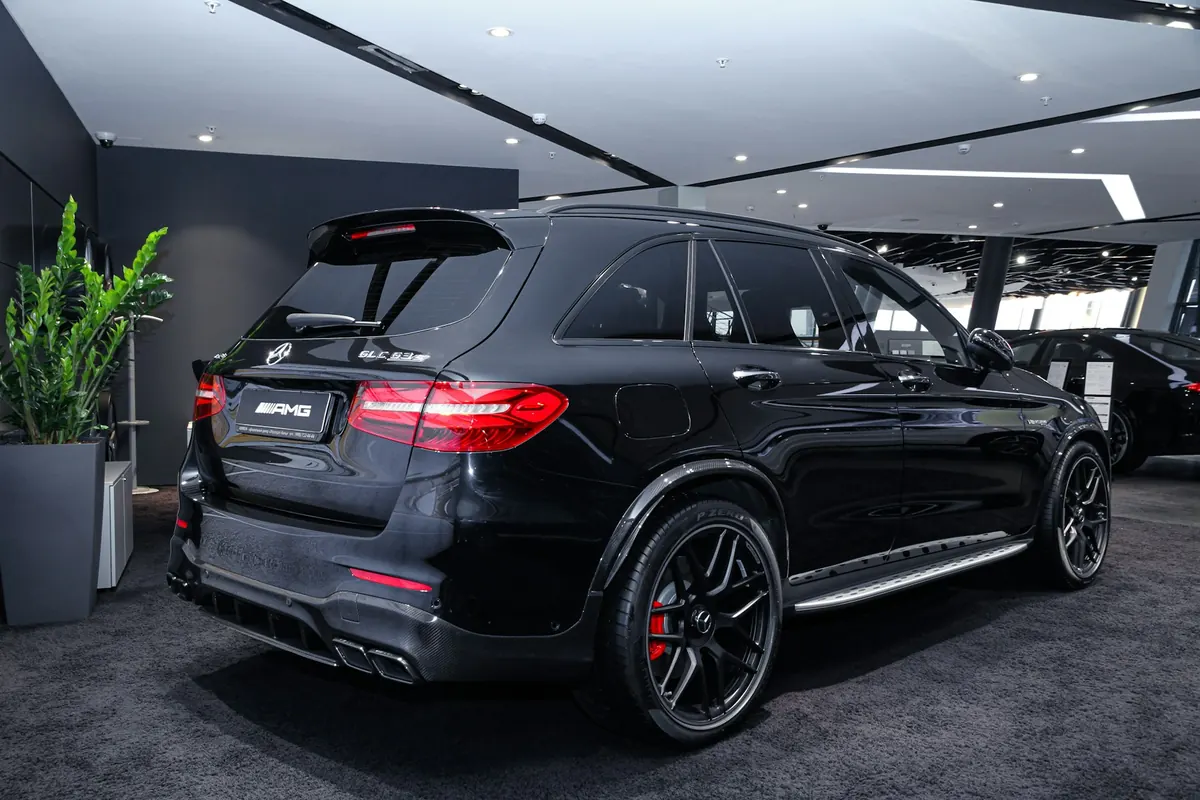 Rear three-quarter view of a black Mercedes-AMG GLC63 S (X253) in a showroom
