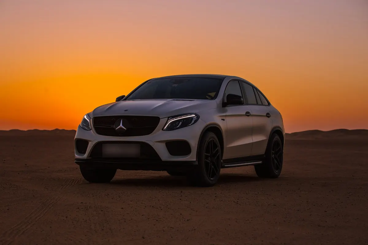 Front three-quarter view of a white Mercedes-AMG GLE43 Coupe (C292) in the desert at sunset