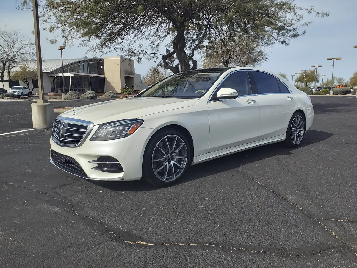 Front three-quarter view of a white Mercedes-Benz S450 (W222) sedan in a parking lot