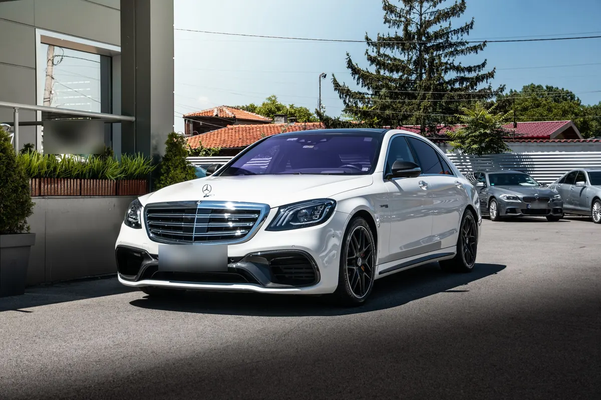 Front three-quarter view of a white Mercedes-AMG S63 (W222) sedan in a parking lot