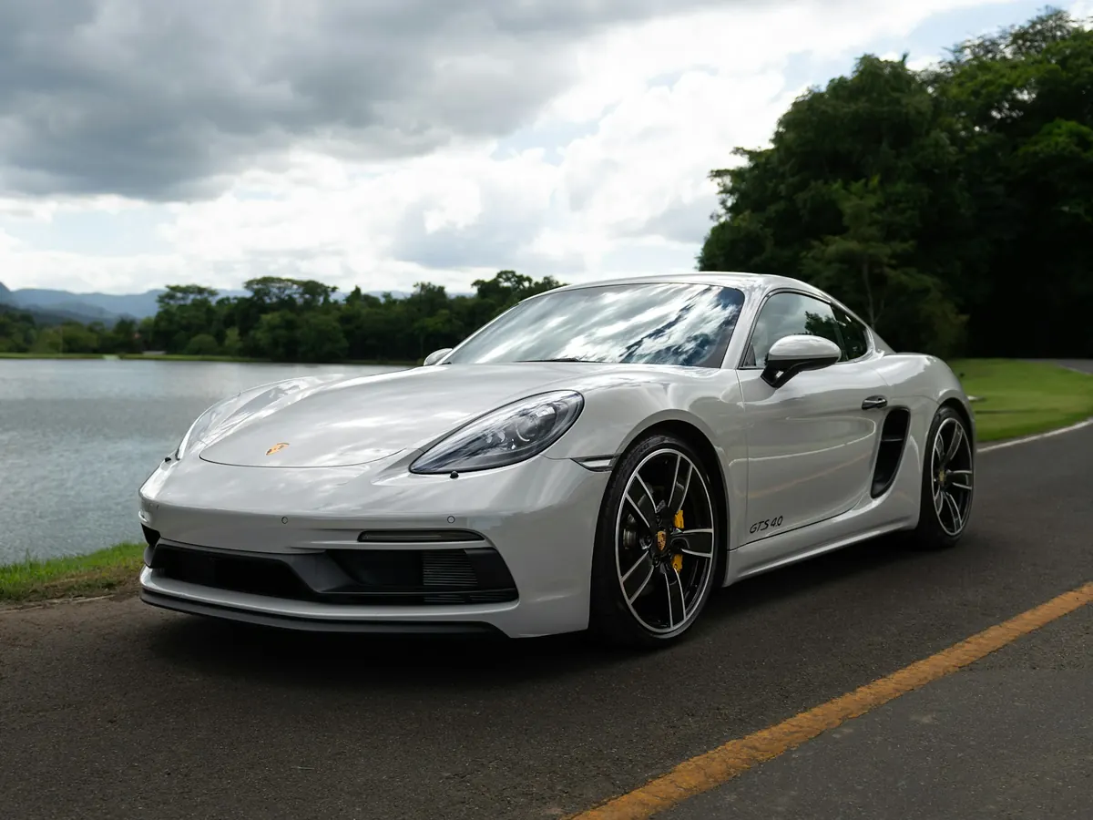 Front three-quarter view of a light grey Porsche 718 Cayman GTS 4.0 parked by a lake
