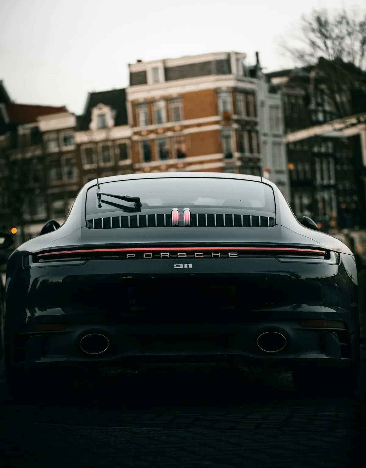 Rear view of a dark grey Porsche 911 Carrera (992.1) on a city street