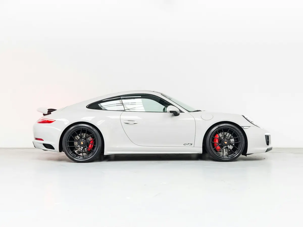 Side view of a white Porsche 911 Carrera 4 GTS (991.2) in a white studio