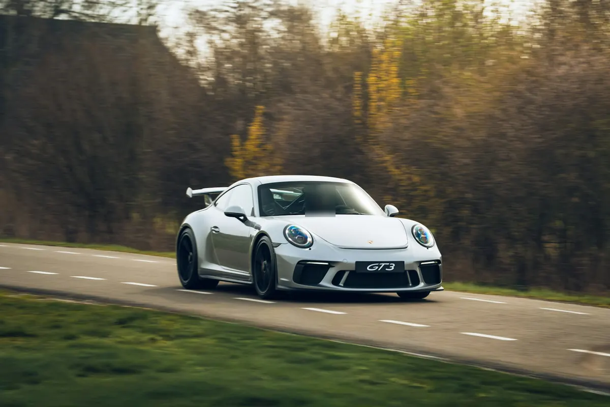 Front three-quarter view of a white Porsche 911 GT3 (991.2) driving on a country road