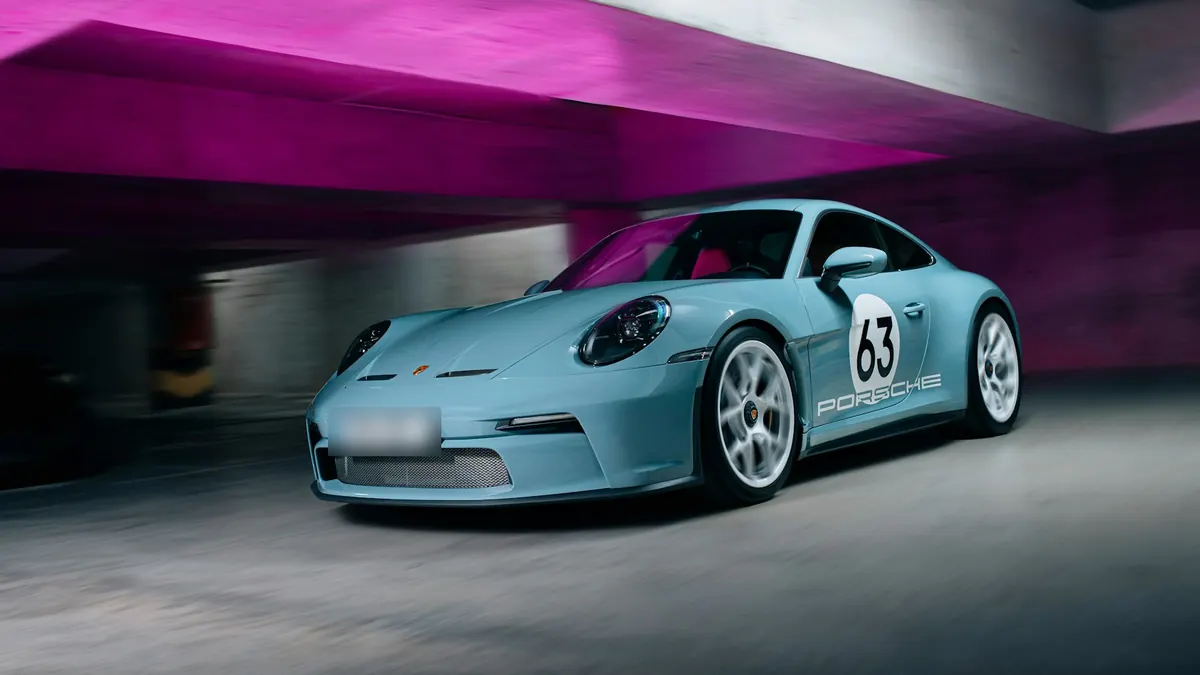 Front three-quarter view of a light blue Porsche 911 S/T (992.1) with race number 63, driving through a parking garage