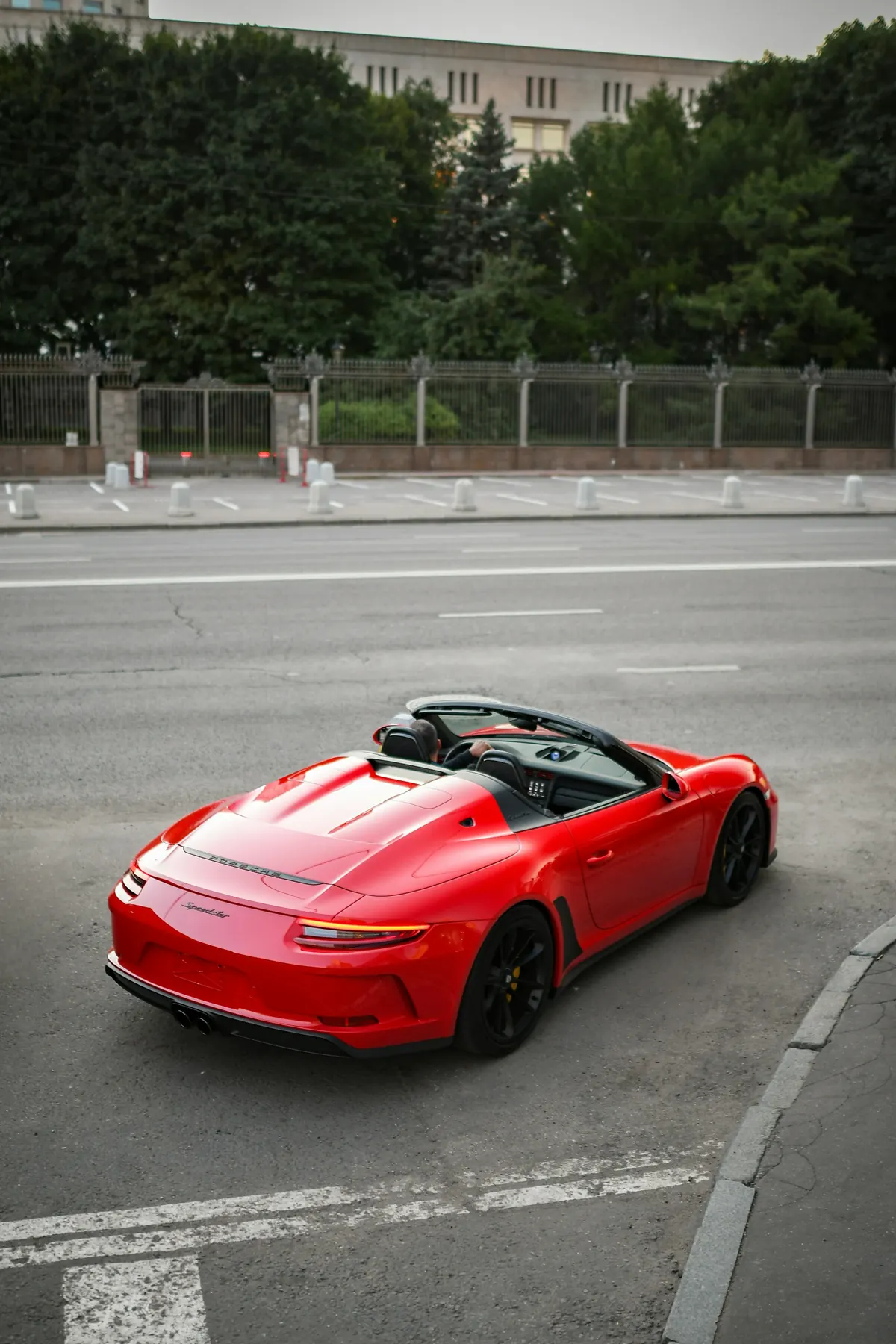 Rear three-quarter view of a red Porsche 911 Speedster (991.2) with its top down, parked by a road