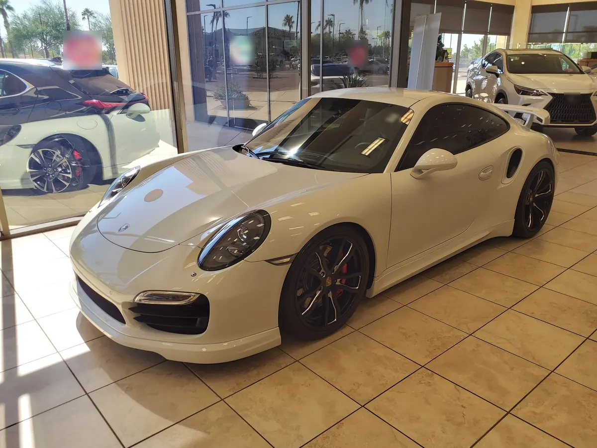 Front three-quarter view of a white Porsche 911 Turbo (991.1) in a showroom